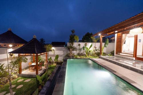 a swimming pool in the backyard of a house at night at Maddu Suites in Ubud