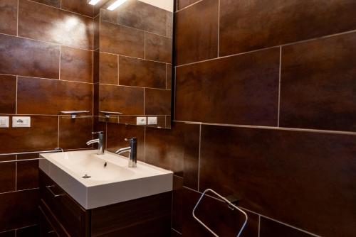 a bathroom with a white sink and brown tiles at Zen Home Zone in Florence