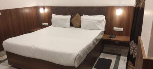 a bedroom with a large bed with white sheets and pillows at Hotel Zen in Khajurāho