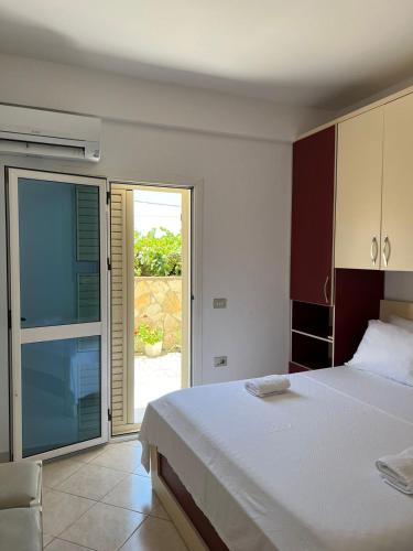 a bedroom with a bed and a sliding glass door at Apartments Rezidenca Sinani Orikum in Orikum