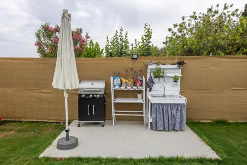 a backyard patio with an umbrella and a grill at Azzure Heaven in Loutrá Elevtherón