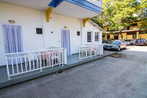 a white building with a porch with chairs on it at Armiriki Rooms in Vrasná