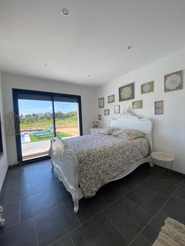 une chambre avec un lit blanc et une grande fenêtre dans l'établissement Villa Sud La Cigale des Bois de Maruéjols, à Mons