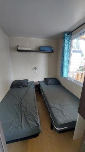deux lits dans une petite pièce avec une fenêtre dans l'établissement camping tohapi les salins, à Vic-la-Gardiole