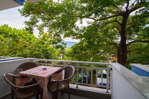 a table and chairs on a balcony with trees at Armiriki Rooms in Vrasná