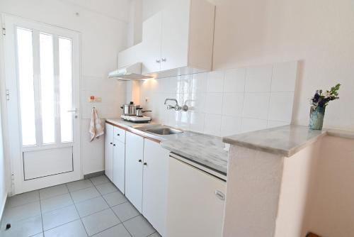 a white kitchen with white cabinets and a sink at Armiriki Rooms in Vrasná