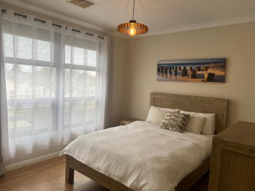a bedroom with a bed and a large window at Modern house between Airport and Sea in Seaton
