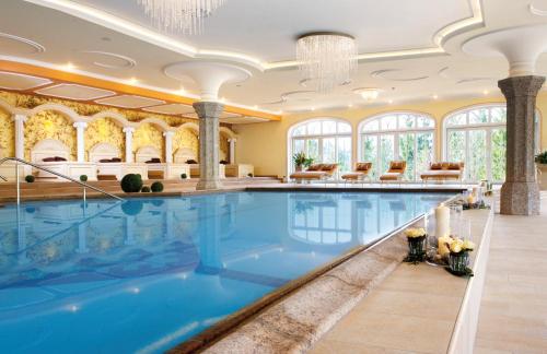 a swimming pool in a hotel with a large room with windows at Der Lärchenhof in Erpfendorf