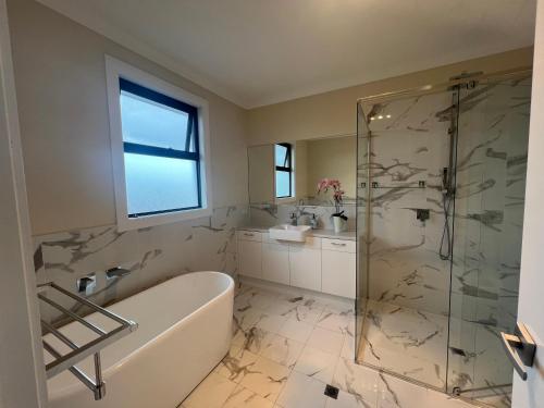 a bathroom with a tub and a glass shower at Modern house between Airport and Sea in Seaton