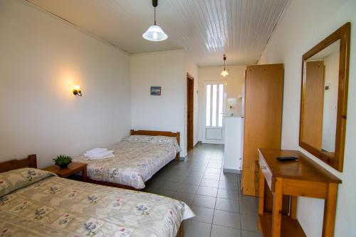 a room with two beds and a table and a mirror at Armiriki Rooms in Vrasná