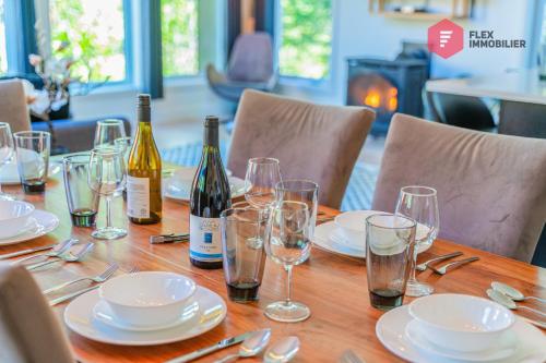 a wooden table with wine bottles and glasses on it at Le Grand Pic de Portneuf - 65" TV, Sonos, SPA, Pool, Fireplace, Billiards in Pont-Rouge
