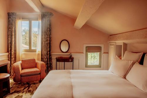 a bedroom with a bed and a chair and a window at Le Mas Candille in Mougins