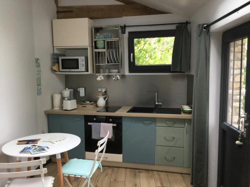 une petite cuisine avec un évier et une table dans l'établissement Petite Maizoun - Gite, à Hermanville-sur-Mer