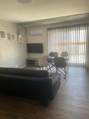 un salon avec un canapé, une table et des chaises dans l'établissement Les 3 clochers, à Pamiers