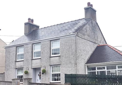 a large brick house with windows and a roof at Bryn Derwen in Caernarfon