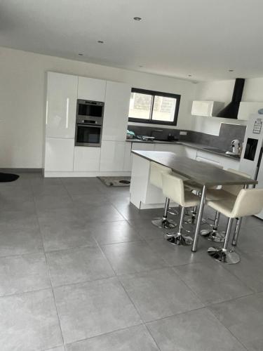 une cuisine avec des armoires blanches et une table et des chaises dans l'établissement Belle villa avec grande piscine, à Villetelle