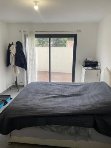 une chambre avec un grand lit et une grande fenêtre dans l'établissement Belle villa avec grande piscine, à Villetelle