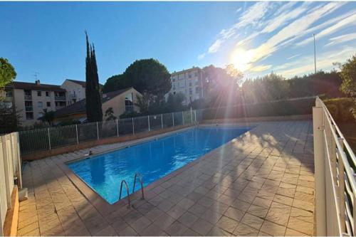- une piscine au coucher du soleil en arrière-plan dans l'établissement Joli T2 avec piscine, à Fréjus