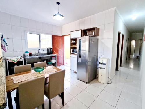 a kitchen with a table and a stainless steel refrigerator at Casa KAIS Peruíbe in Peruíbe