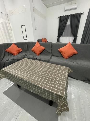 a couch with orange pillows on it in a living room at Homestay Alyaa Bera Triang in Teriang