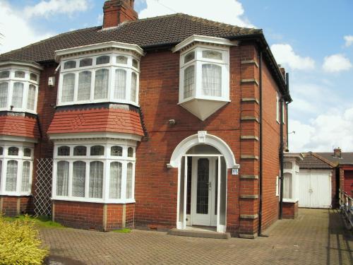 a red brick house with white windows and a door at Dovehouses in Redcar