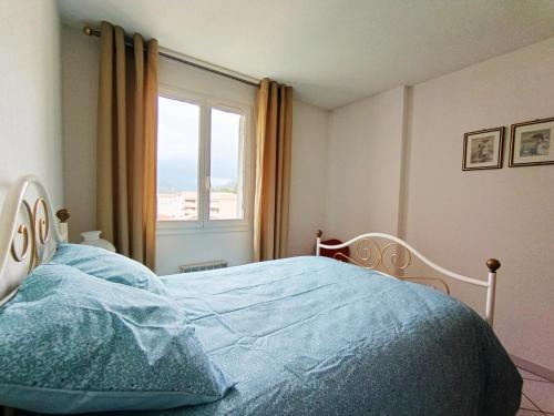 une chambre avec un lit avec des draps bleus et une fenêtre dans l'établissement Terrasse du Laurier - Centre-ville - ascenseur, à Digne-Les-Bains