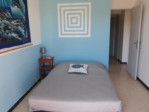 un lit dans une chambre avec un mur bleu dans l'établissement Belle Vue, à Palavas-les-Flots