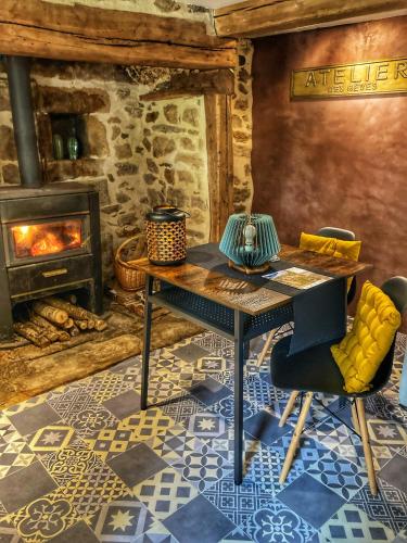 - une table et des chaises dans une pièce dotée d'une cheminée dans l'établissement L'Atelier des Rêves, à Saint-Martial-Entraygues