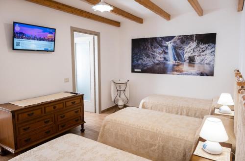 a bedroom with two beds and a tv on the wall at B&B Ruinas in Arzana