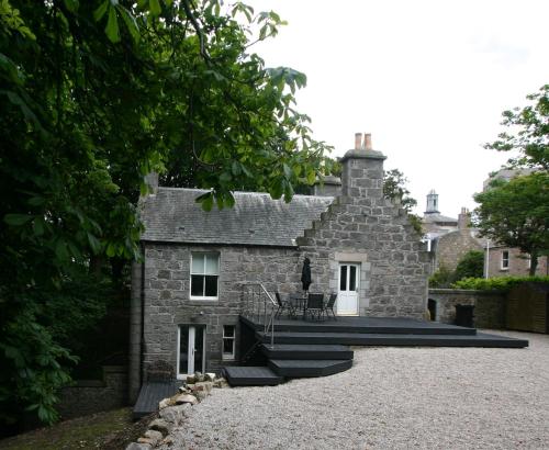an old stone house with a patio in front of it at Historic Baronial Lodge with Parking, Aberdeen City Centre in Aberdeen
