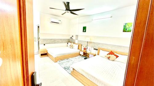 a room with two beds and a ceiling fan at ALOHA SAIGON PREMIUM HOSTEL by Local Travel Experts - Newly opened, Less-touristy location, Spacious rooms, Glass shower bathroom, Free breakfast & Walking Tour in Ho Chi Minh City