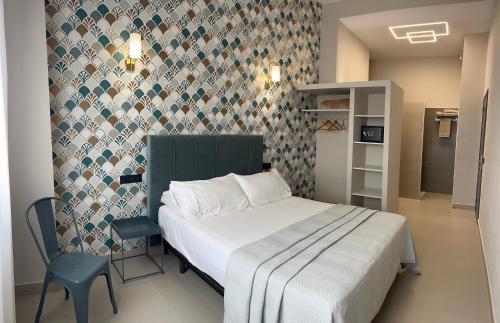 a small bedroom with a bed and a chair at La LIPA in Almáchar