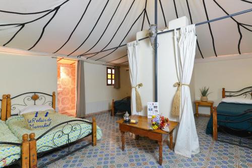 a bedroom with two beds and a table in a room at Le Relais De Marrakech in Marrakech