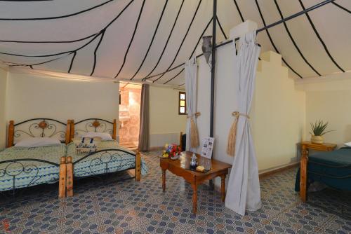 a bedroom with a canopy bed and a table at Le Relais De Marrakech in Marrakech