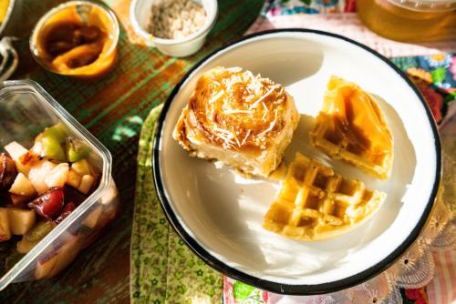 a plate of food with waffle and waffles and a container of fruit at Flores da Mantiqueira in Monte Verde