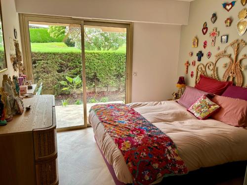 une chambre avec un lit et une grande fenêtre dans l'établissement Superbe 3P bohème, Juan les pins, jardin, 900m de la mer, à Antibes