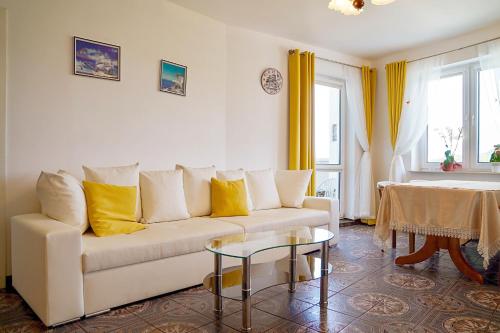 a living room with a white couch and yellow pillows at Chrobry by Baltic Home in Międzyzdroje