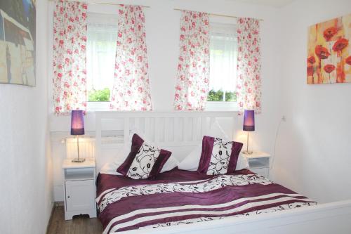 a bedroom with a bed and two windows at City Ferienhaus Vulkaneifel in Daun