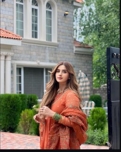 a woman in an orange dress standing in front of a house at Arish Luxury Suites in Skardu