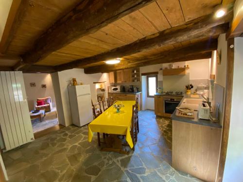 une cuisine avec une table jaune au milieu dans l'établissement Les Gîtes de l'Abric, à LʼEstréchure