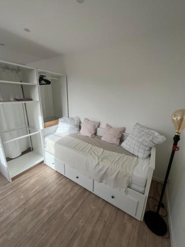 une chambre avec un lit blanc avec des oreillers roses dans l'établissement Studio Intra-Muros idéal festivalier Climatisé, à Avignon