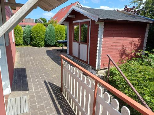un pequeño edificio rojo con una valla y una mesa en Ferienhaus Dittrich, en Eckernförde