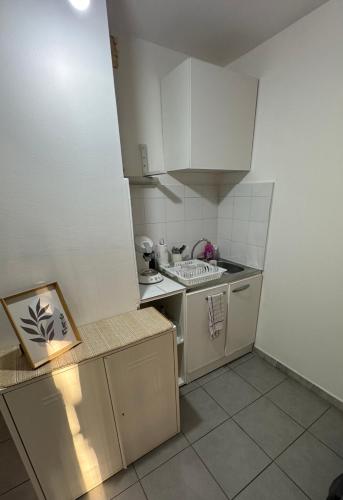 une petite cuisine avec des armoires blanches et une cuisinière dans l'établissement Studio à Marseille avec Terrasse, à Marseille