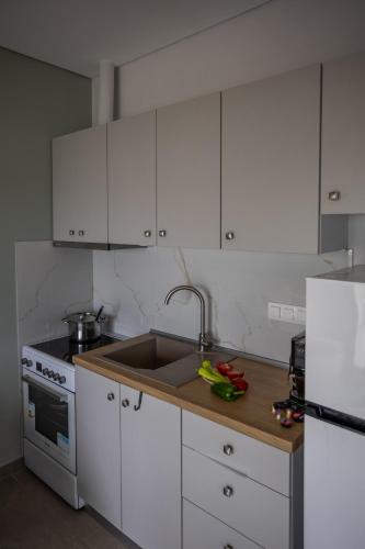 a white kitchen with a sink and a refrigerator at Azzure Heaven in Loutrá Elevtherón