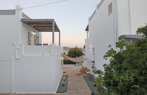 a hammock hangs from the side of a white building at Galini Rooms & Apartments in Finikas