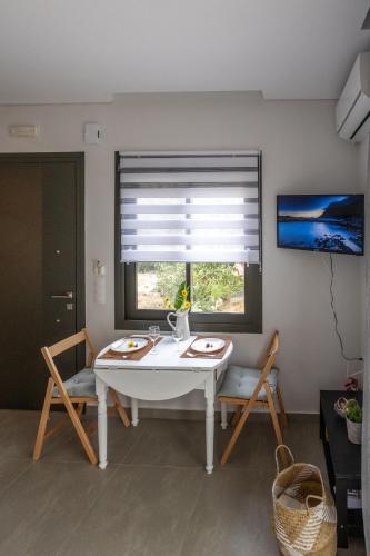 a white table and chairs in a room with a window at Azzure Heaven in Loutrá Elevtherón