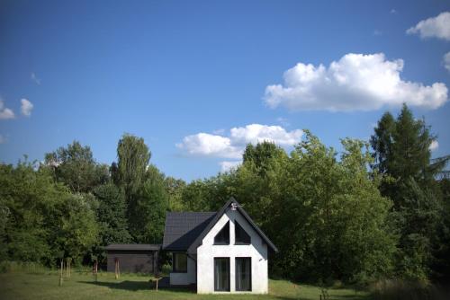 a small white house with a black roof at Domki na polance in Horyniec Zdrój