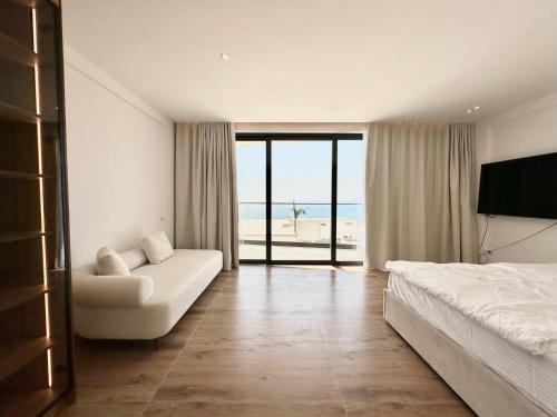 a bedroom with a bed and a couch and the ocean at Palmera Resort Saranda - Palmera Villa Resort in Sarandë