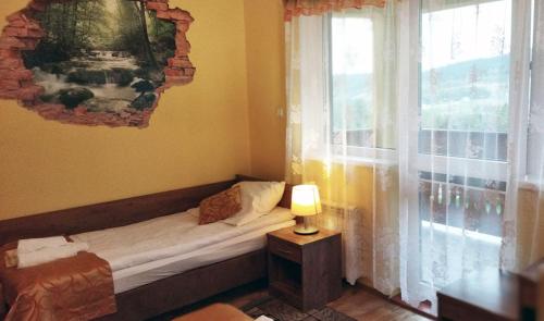 a small bed in a room with a window at Pensjonat Zielone Wzgórze w Bolesławowie in Stronie Śląskie