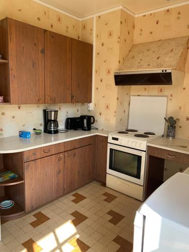 une cuisine avec des armoires en bois et un four blanc dans l'établissement Les Cormiers, à Chailles